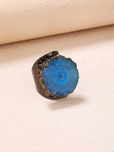 Macro detail of a wide vintage bronze ring with blue crystal flower and textured metal
