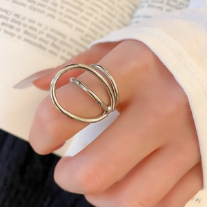 Detail of silver geometric layered ring worn on index finger over a vintage book