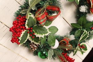 Detail of Christmas wreath with red berries, pine cones and festive checkered bow decor