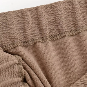 Detail of brown wave knit fabric showing the elastic waistband and fine rolled hem stitching