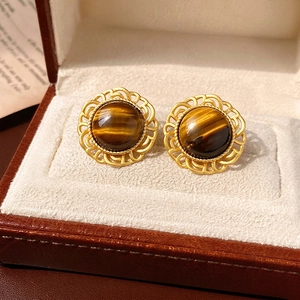 Vintage round tiger eye earrings with golden wavy frame on a velvet jewelry box