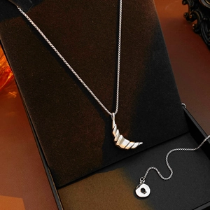 Detailed view of silver crescent pendant with spiral texture on black jewelry display