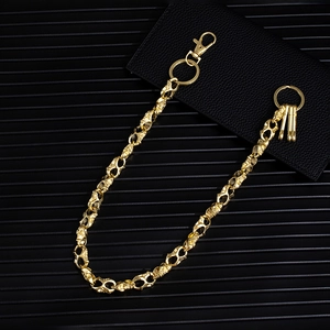 Hip hop style gold skull trouser chain with lobster clasp on a dark textured background