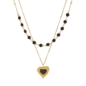 Double-layered gold necklace with black beads and a textured heart pendant on white background