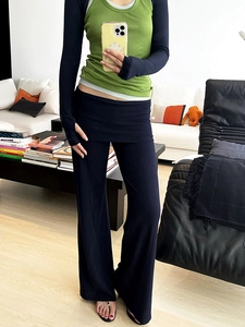 Détail d'un pantalon évasé bleu foncé cintré avec un débardeur en maille verte