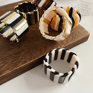 Close-up of geometric acrylic stretch bracelets on a premium wooden display base