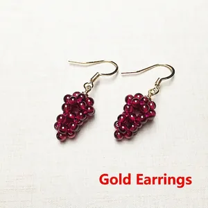 Macro detail of handmade burgundy garnet grape cluster earrings with gold plated hooks