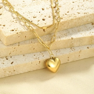 Detail of gold double-layered paperclip and rope chain with 3D heart pendant on stone