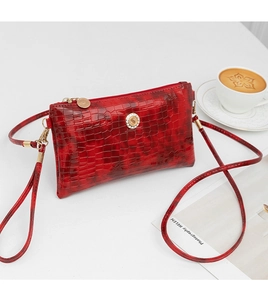 Detail view showing the elegant bamboo pattern and crystal hardware of this red crossbody bag