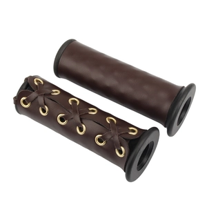 Detail of vintage brown leather motorcycle grips with braided texture and gold eyelets