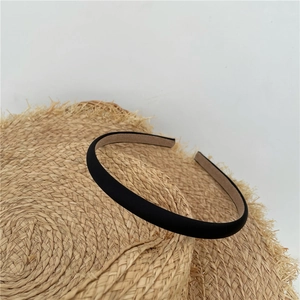 Detail of a minimalist black fabric headband placed on a straw hat for styling