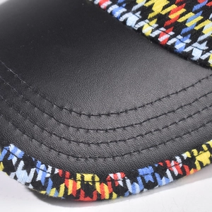 Close-up of baseball cap featuring black PU leather brim with colorful plaid fabric detail