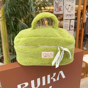Close-up of neon green teddy fleece makeup bag with dual zippers and woven label