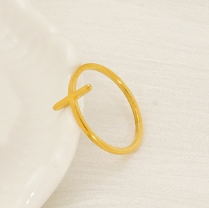 Close-up of minimalist 18K gold plated cross ring hanging on a white porcelain dish