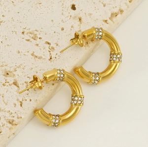 Détail macro de boucles d'oreilles C plaquées or 18 carats avec rangées de zircons