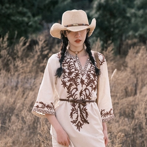 Bohemian beige embroidered dress with western straw hat in natural outdoor landscape