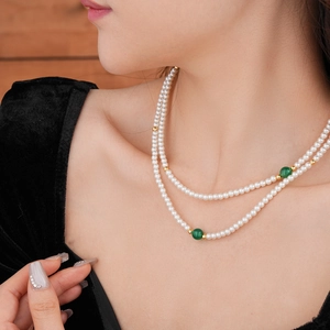 Detail view of double-layered pearl necklace with green agate beads on model neck