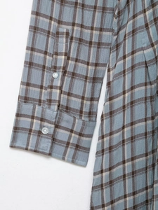 Detail view of plaid shirt dress cuffs featuring translucent buttons and fabric texture