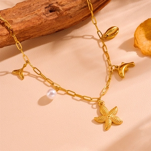 Détail du collier trombone doré avec breloques étoile de mer, dauphin, coquillage et perle
