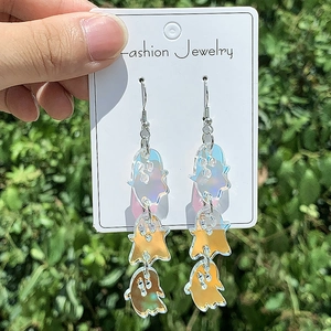 Ghost drop earrings in colorful acrylic material held in hand against green leaves