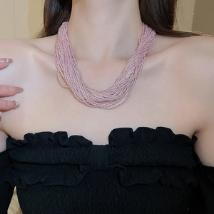 Close-up of multi-layer soft pink bead necklace on female neck for a layered aesthetic