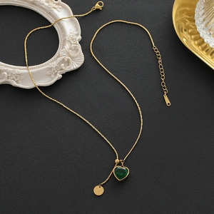 Luxurious gold heart necklace with emerald green gemstone on a vintage textured backdrop