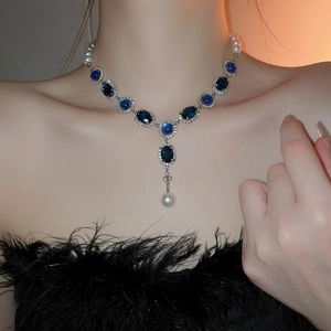 Détail d'un collier en Y avec pierres précieuses bleu foncé et perles blanches sur mannequin