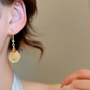 Detailed view of elegant gold flower earrings with crystals worn by a model in warm light