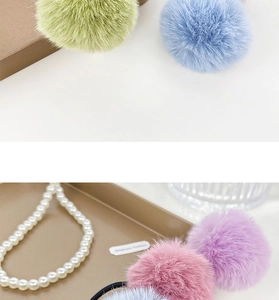Close-up of soft green and blue plush pom pom hair ties with elastic black bands