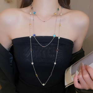 Detailed view of multilayered stainless steel necklace with colored gems and white pearls