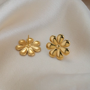 Detail of flower stud earrings in 18K gold finish on elegant beige silk background