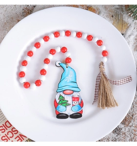 Close-up of Christmas gnome wooden beads ornament with hemp tassel on white plate