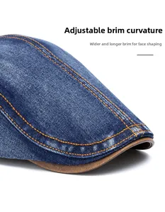 Detail of washed denim flat cap showing orange double stitching and foldable brim