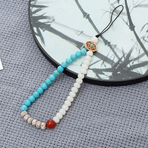 Detailed macro of white bodhi beads and blue turquoise stones on a phone lanyard