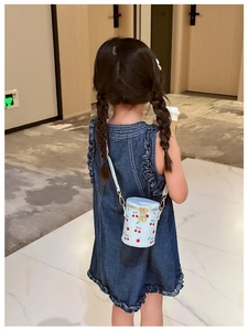 Girl wearing light blue cherry bucket bag with golden chain strap and cartoon print