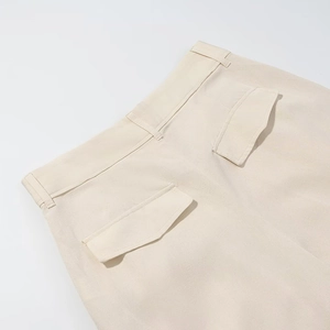 Dettaglio dei pantaloni a gamba larga a vita alta con tasche posteriori e tessuto beige