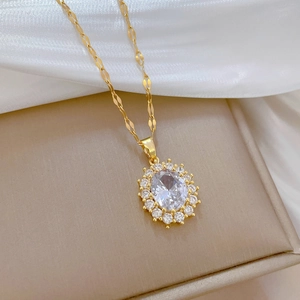 Close-up of gold oval crystal necklace with zircon halo on beige jewelry box