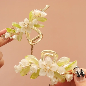 Detail of floral hair claw clips with white petals, green leaves, pearls and tassel chains