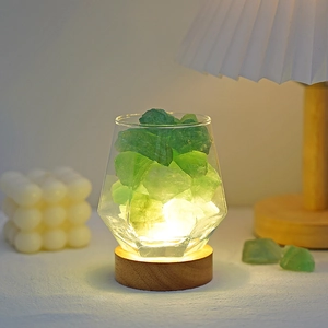 Detail of green crystal stones in a geometric glass jar with warm LED wooden base