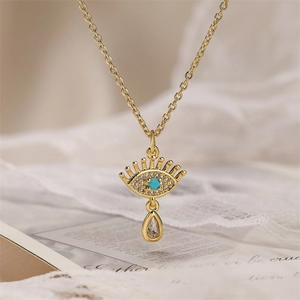 Détail du collier œil protecteur doré avec pierre turquoise et pendentif en cristal