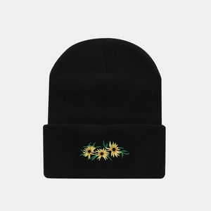Close-up of yellow daisy embroidery on a black knitted beanie with clear texture