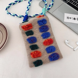 Detail of a handmade knit bag with colorful wool felt accents and woven cord strap