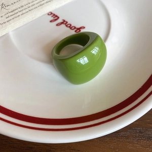 Detailed top view of a glossy green resin oval ring on a white ceramic plate