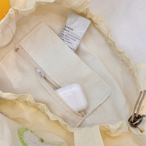 Detail view of the beige drawstring tote's interior canvas zip pocket and lining