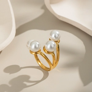 Elegant geometric gold tiered ring with four white pearls on a minimalist stone base