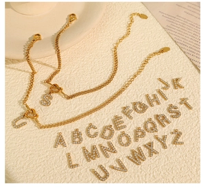 Detailansicht von 26 goldenen Buchstaben-Anhängern mit Zirkonia und zwei Armbändern