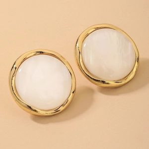 Detail view of round resin stud earrings with golden metal frames and white textured inlay