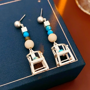 Detailed close-up of vintage chair-shaped drop earrings with colorful beads on a box