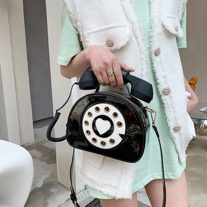 Detail of vintage rotary telephone shaped crossbody bag in glossy black patent leather