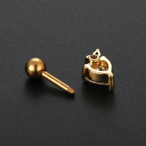 Golden heart piercing stud with zircon and screw ball back on dark textured surface